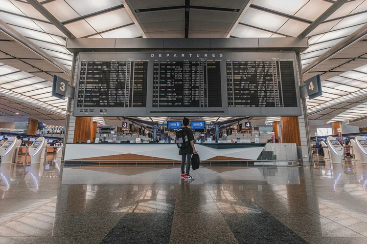Traveler standing before a large digital departures board in a modern airport terminal