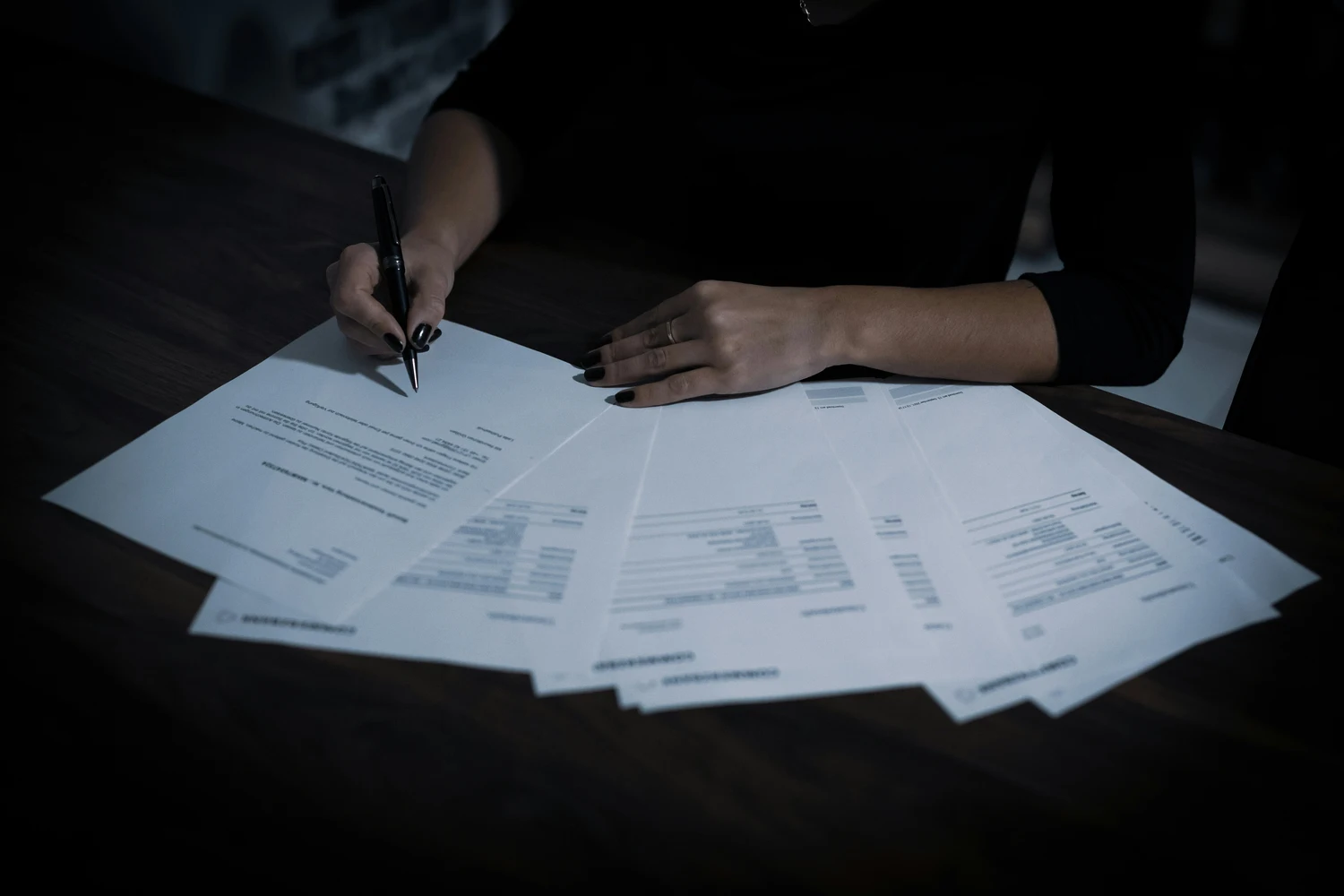 Hands reviewing multiple pages of a commercial contract on a dark desk — penalty clause under Article 551 of the Ukrainian Civil Code
