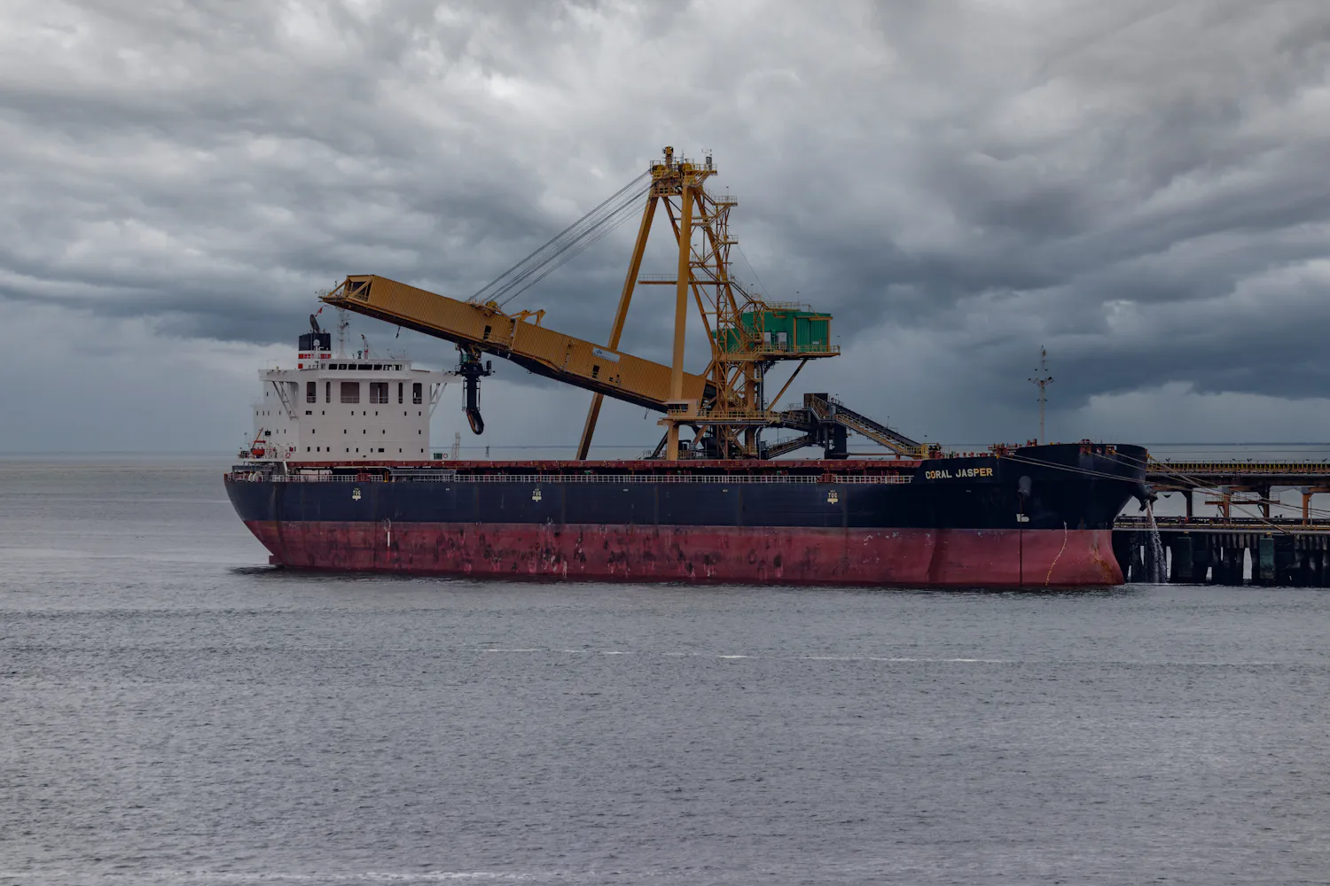 Bulk carrier at a loading terminal under a storm sky