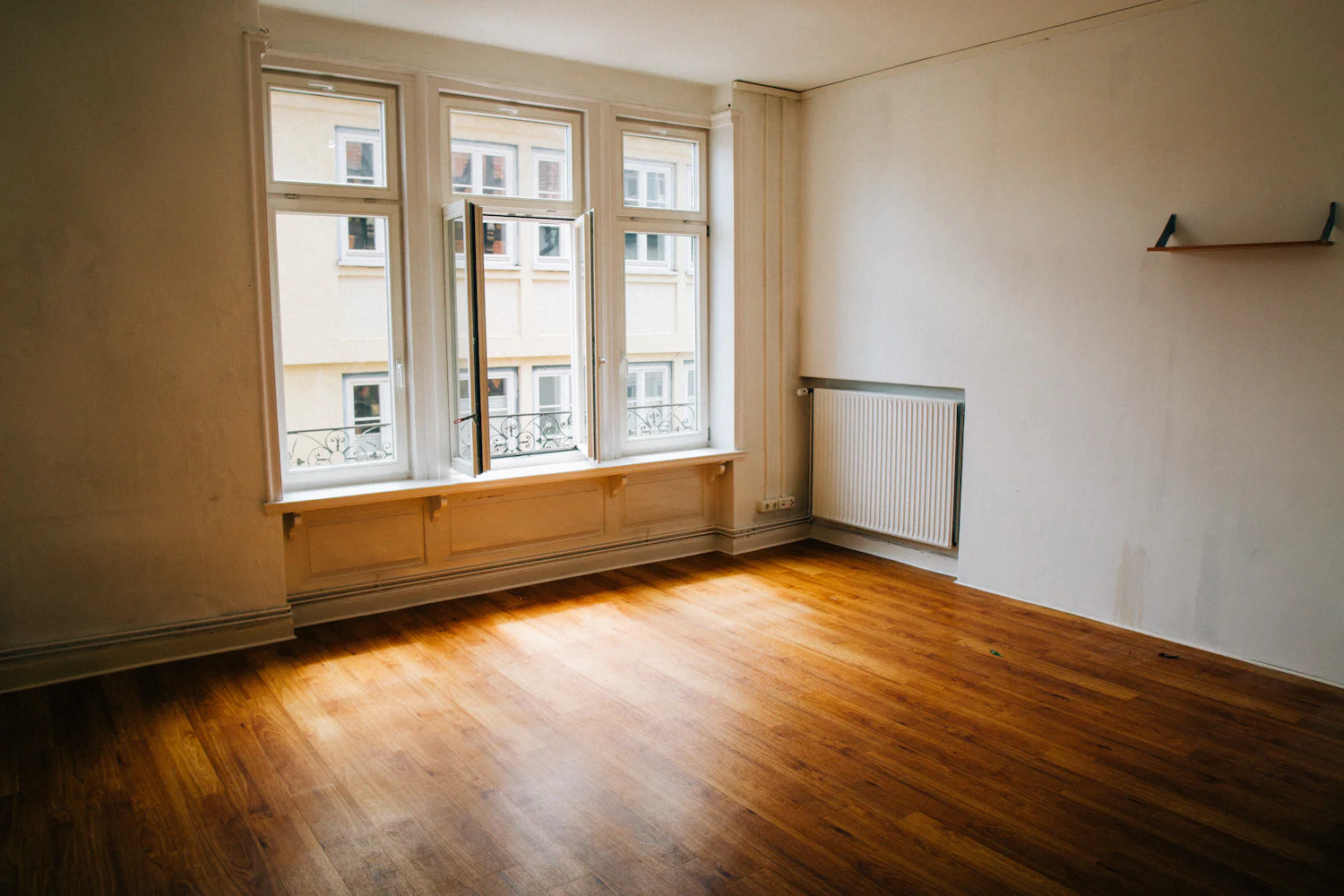 An empty apartment with parquet floor and tall windows