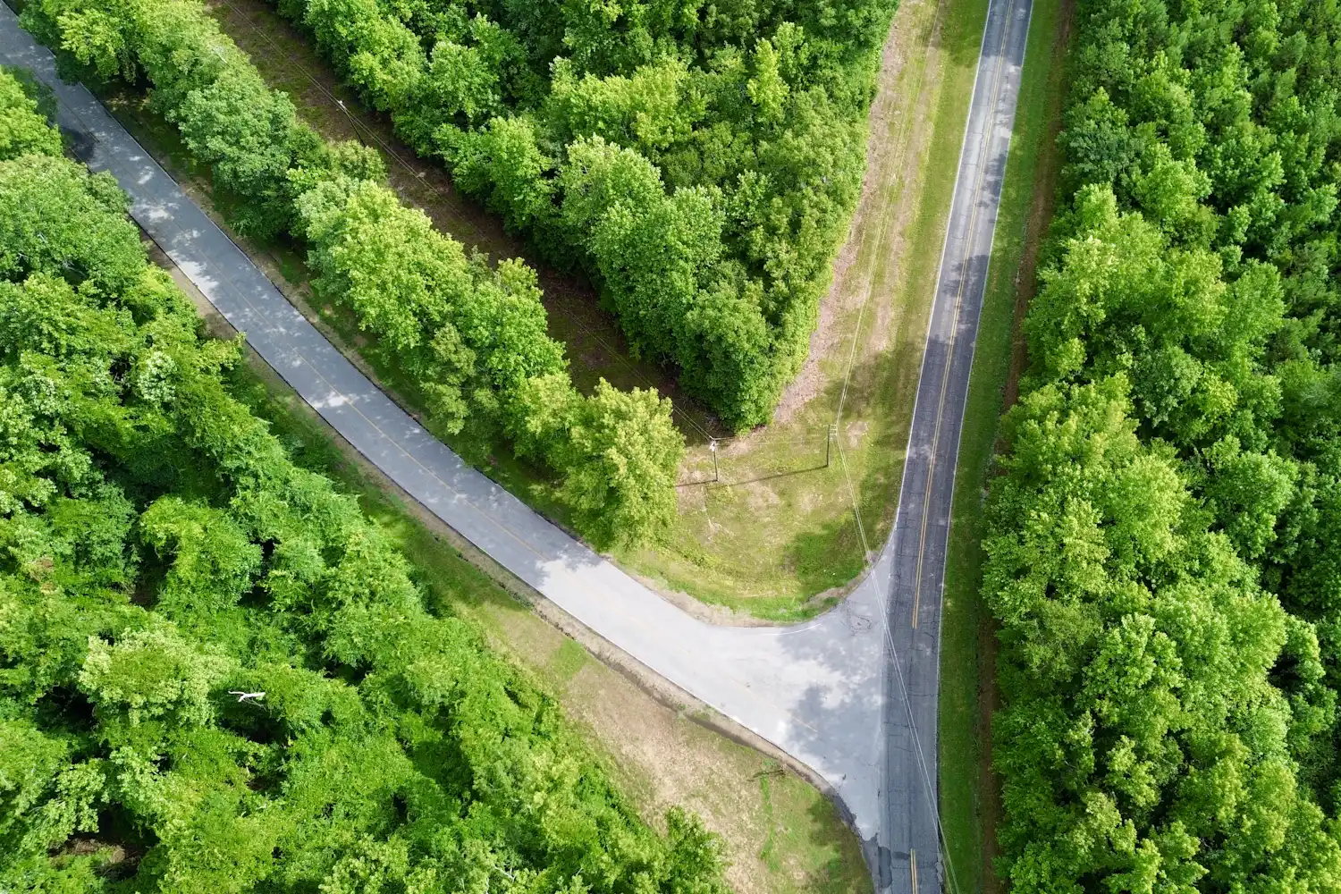 Aerial view of a minor road joining a main road in a forest